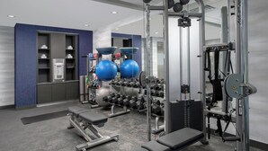 A gym with exercise equipment, benches, and weight racks.