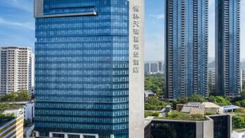 A Sheraton hotel with a modern glass facade, surrounded by high-rise buildings and greenery.
