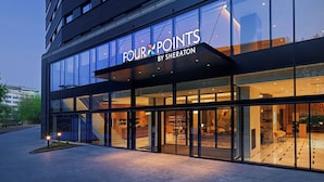 A modern hotel exterior with large glass windows, a visible staircase, and a sign reading "FOUR POINTS BY SHERATON". - Four Points by Sheraton Warsaw Mokotow (Warsaw)