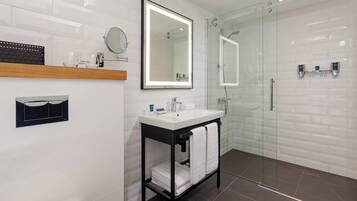Une salle de bain moderne avec une douche à parois de verre, un lavabo blanc avec un miroir et un meuble-lavabo noir.