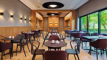 A modern dining area with wooden paneling, black and red chairs, and tables set with white teapots and cups.