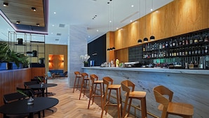 A modern bar area with wooden bar counters, bar stools, and a variety of bottles. - Four Points by Sheraton Warsaw Mokotow (Warsaw)