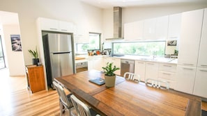 A modern kitchen with white cabinets, stainless steel appliances, and a wooden dining table.