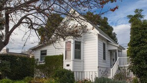 A white two-story house with a front porch and a small staircase leading to the entrance. - Summerland Stagecoach Cottage - A Historic Treasure in Summerland (Summerland)