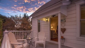 A white wooden house with a porch featuring two white Adirondack chairs and a small table. - Summerland Stagecoach Cottage - A Historic Treasure in Summerland (Summerland)