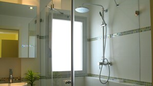 Une salle de bain avec une douche à parois de verre, un lavabo blanc et un miroir.