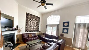Een woonkamer met een open haard, leren banken, een salontafel en een televisie.