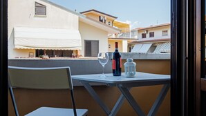Un balcon avec une table, une chaise, une bouteille de vin et un verre.
