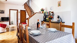 Un coin repas avec une table dressée pour quatre personnes, un escalier, une bibliothèque et un téléviseur en arrière-plan.