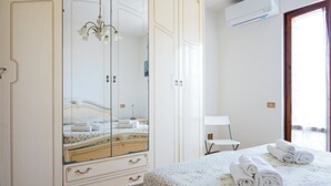 Une chambre à coucher avec un lit, une armoire, un miroir et une fenêtre.
