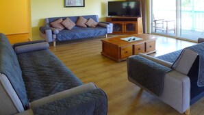 A living room with a sofa, a coffee table, and a television on a wooden cabinet. - * * * Aquamarine * * *
Right next to the beach (Baudin Beach)