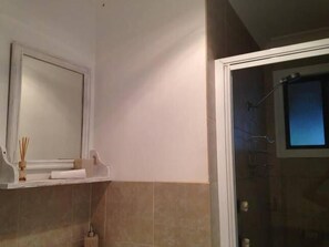 Een badkamer met een spiegel, een handdoekhouder en een douchehoek.