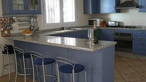 Una cocina con una isla central, taburetes de bar, microondas, tostadora y estufa.