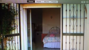 Una habitación con una cama, una ventana y una puerta con rejas decorativas de metal.