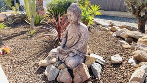 Un jardín con una estatua de Buda rodeada de rocas y plantas.