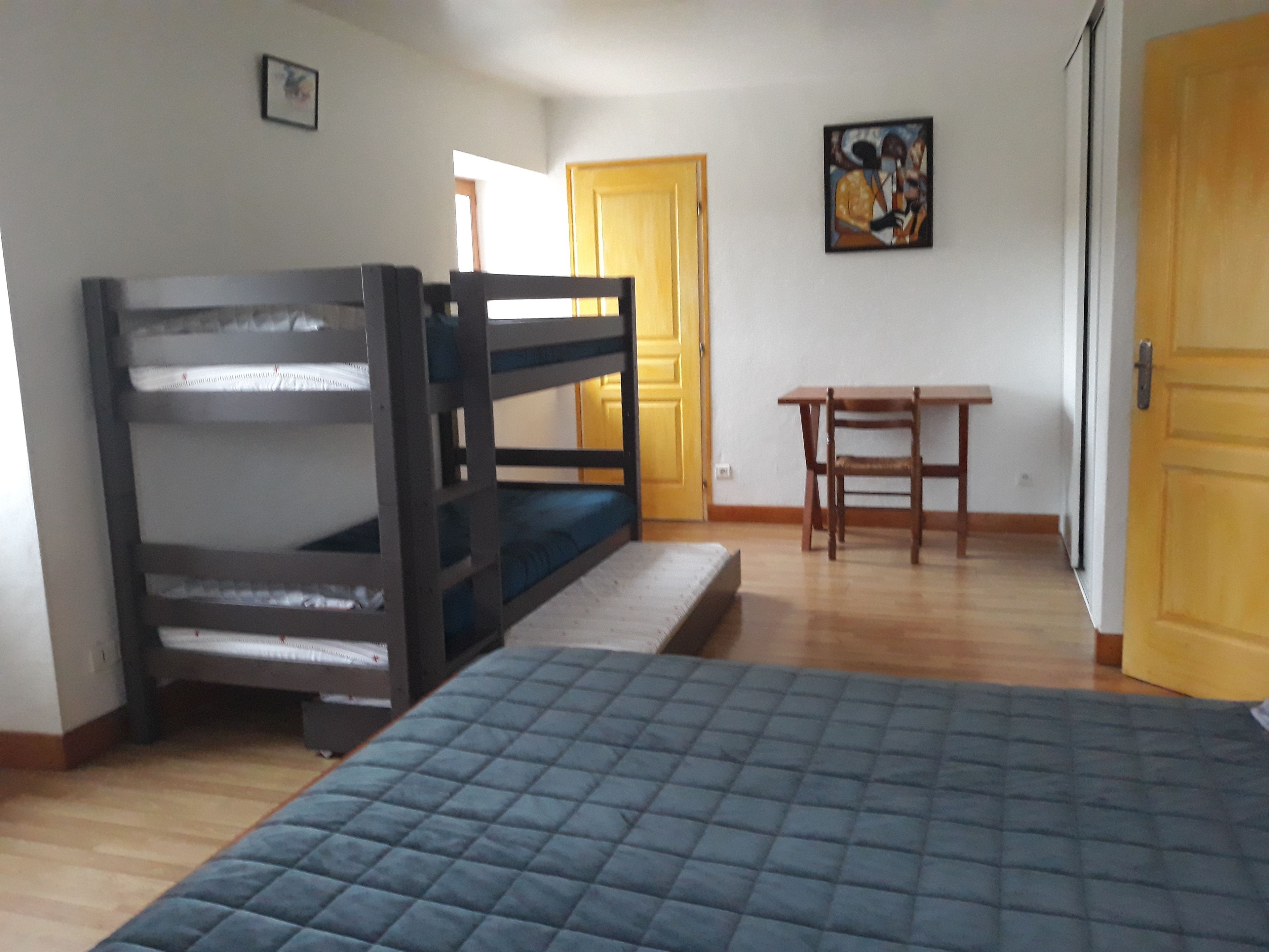 A room with bunk beds, a desk, and a door.