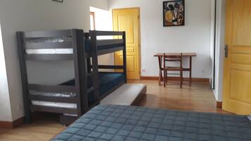 A room with bunk beds, a desk, and a door.