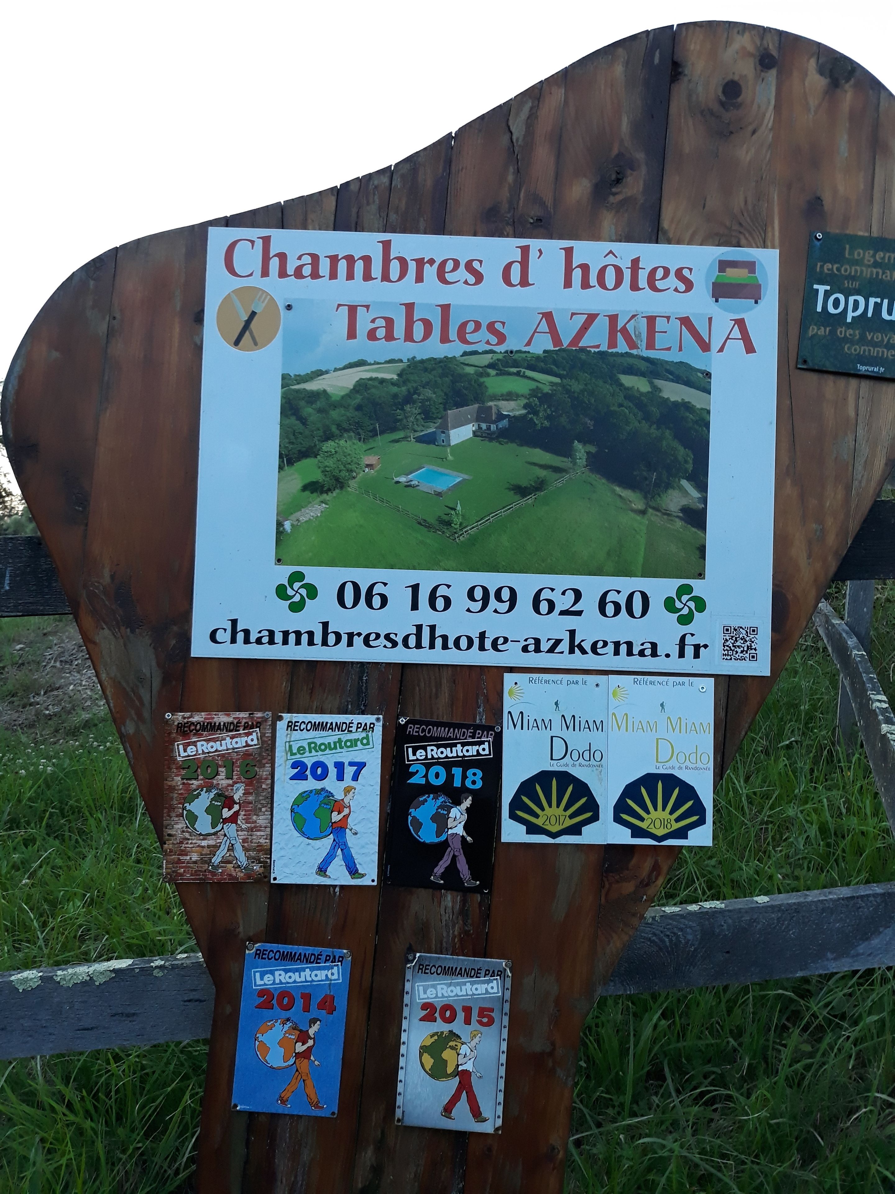 A wooden sign with a picture of a house and a pool, a phone number, and several stickers with logos and years.