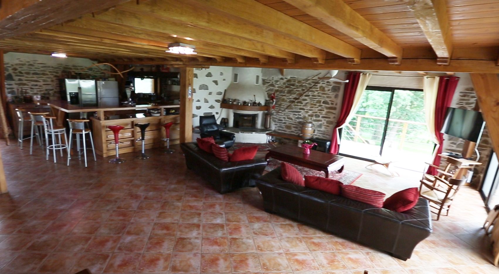Un espacio de sala acogedor con chimenea, asientos y una cocina al fondo.