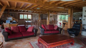Amplia sala de estar con vigas de madera, chimenea, comedor y un rincón de asientos acogedor.