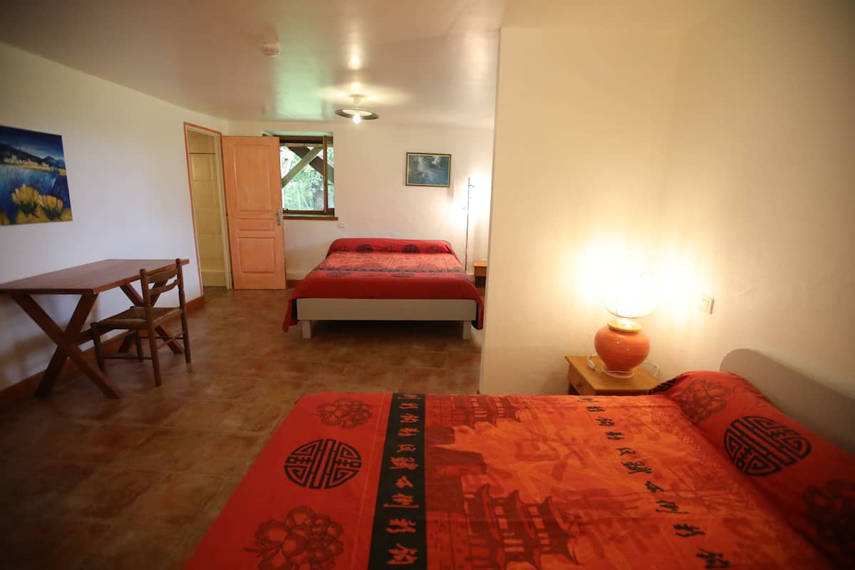 A bedroom with a bed, a desk, and a chair.