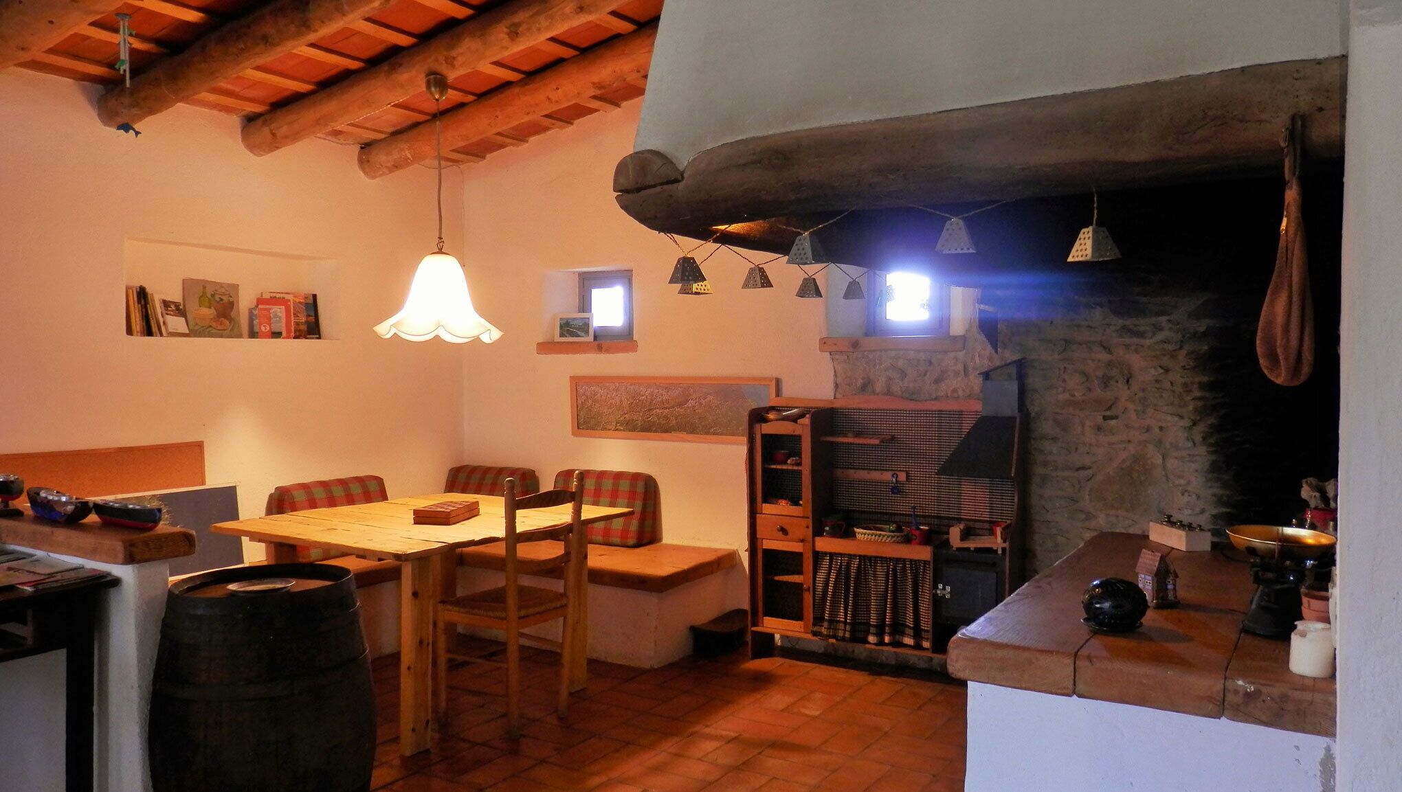 Un comedor rústico con una mesa y bancos de madera, un colgador de luz y una pared de piedra con chimenea.