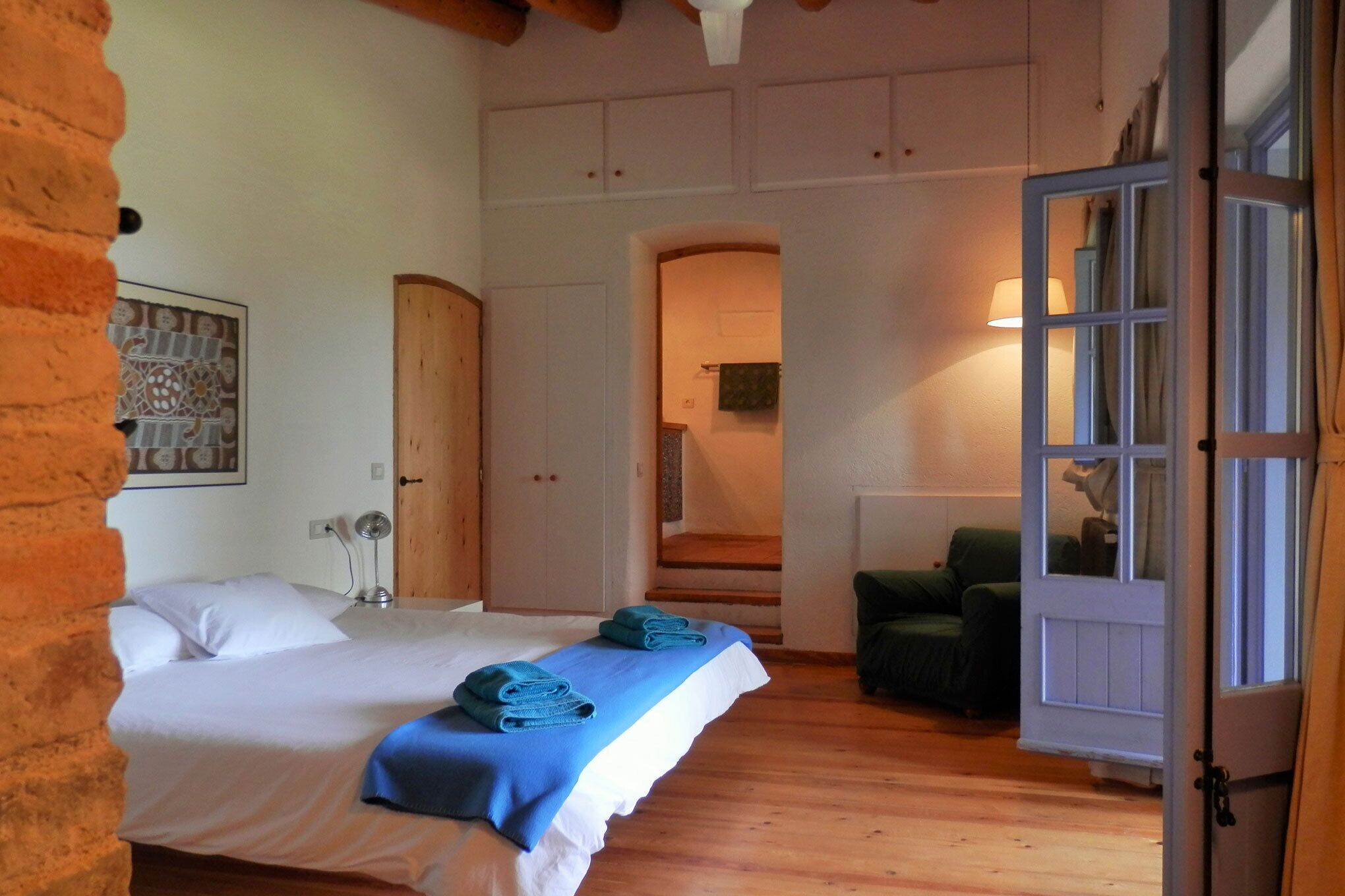 Una habitación con una cama, una silla, una puerta y una escalera.