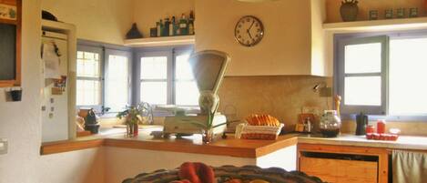 Una cocina con un ventanal grande, un reloj en la pared y varios utensilios de cocina sobre la encimera.