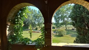 A view through an arched window of a garden with a lawn, trees, and a small pond. - Stunning property isolated, surrounded by nature, 5 min to beaches. Max privacy. (gualta)