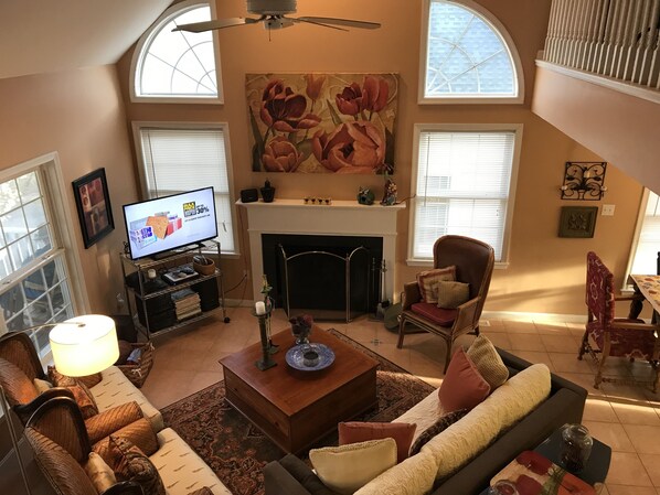 A living room with a fireplace, a television, and a high ceiling with skylights.