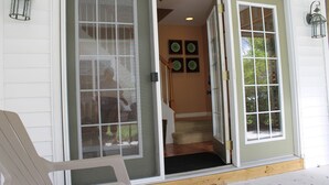 A house entrance with a sliding glass door, a wooden porch, and a staircase leading inside. - Close to Beach! 2026 Prime Weeks Available!  Family Oriented Home! Dogs Welcome! (Bethany Beach)