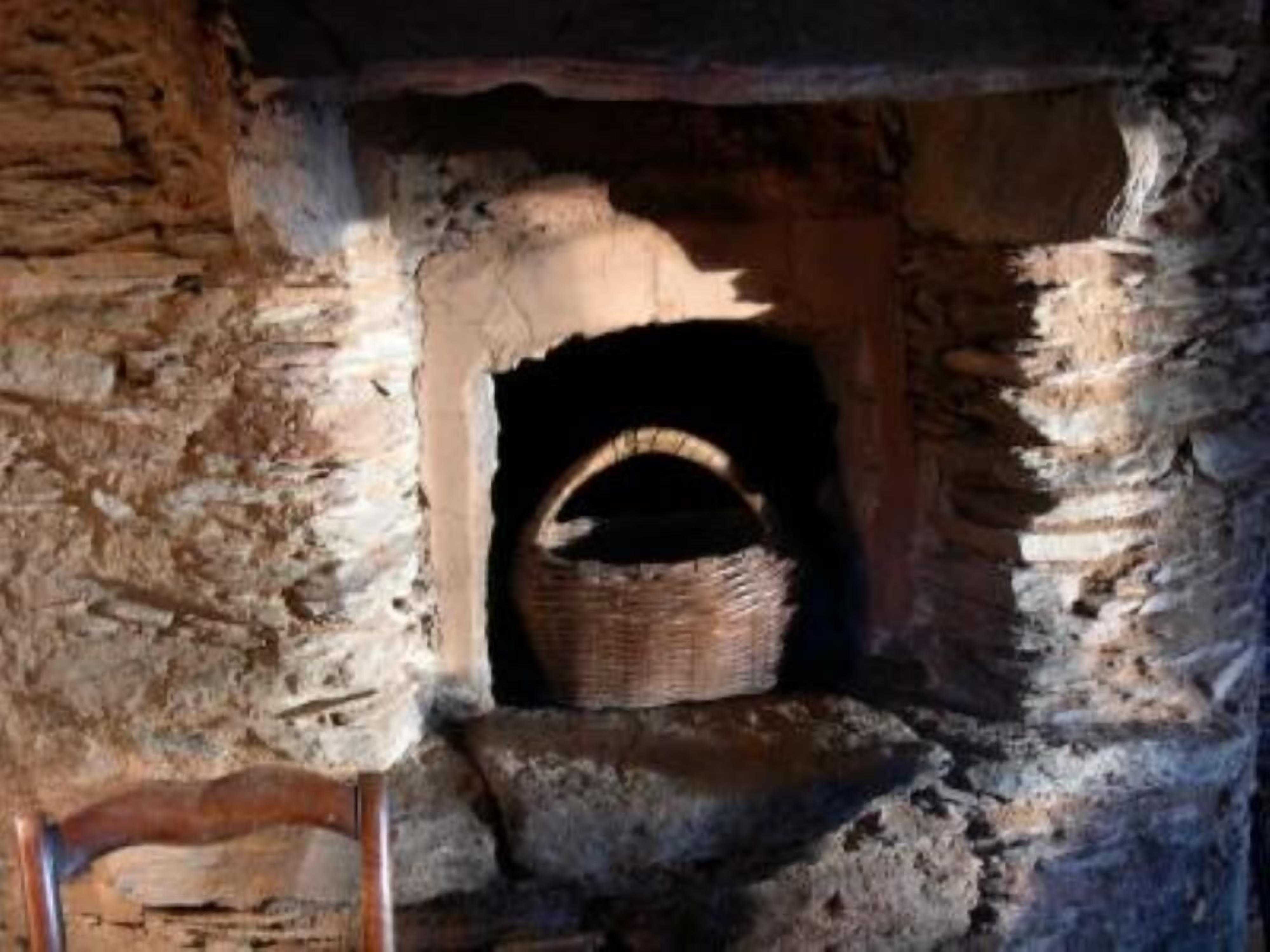 A stone fireplace with a woven basket inside.