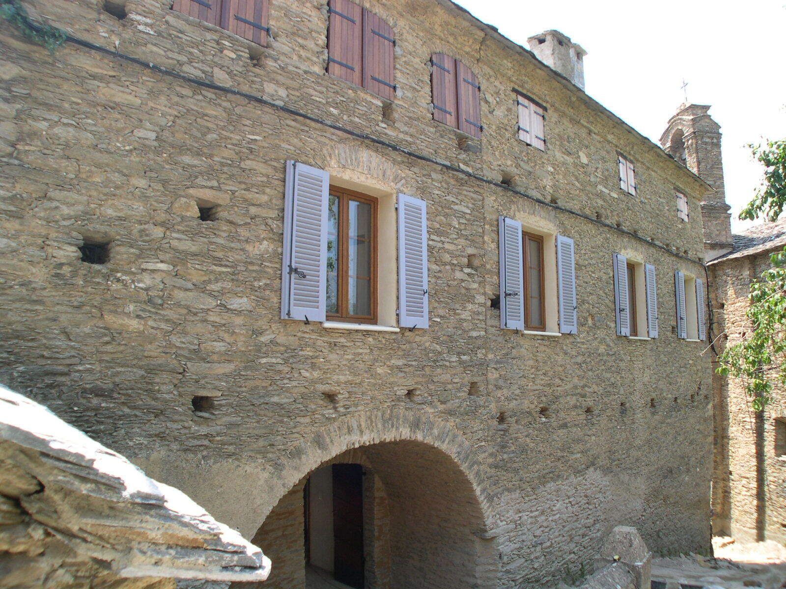 Un edificio in pietra con aperture ad arco e persiane.