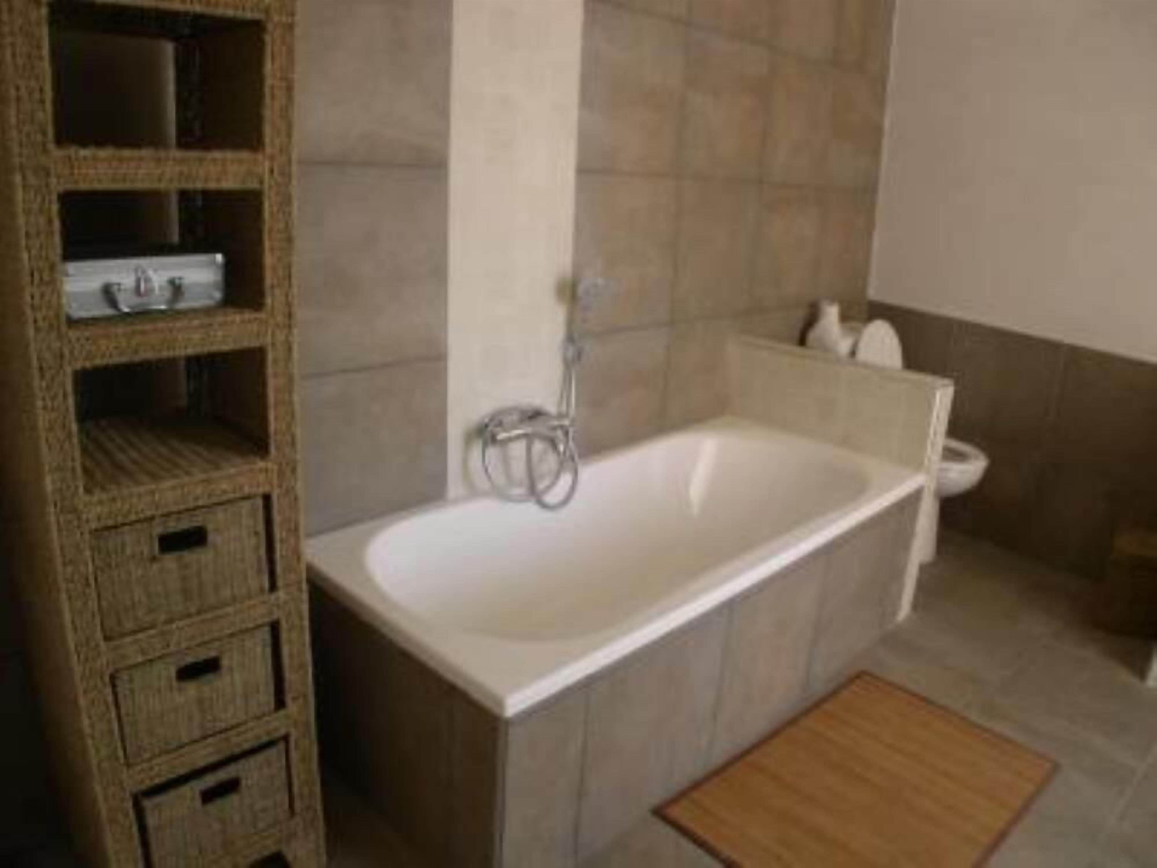 A bathroom with a bathtub, a wooden shelf unit, and a toilet.