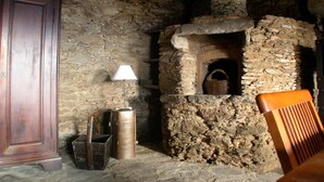 A rustic stone room with a fireplace, a wooden cabinet, and a lamp. - Castineta: mansion - CastinetaHouse with character (Castineta)