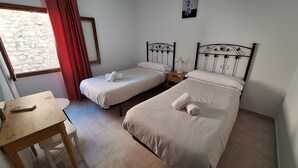 A room with two single beds, a wooden desk, and a window with red curtains. - Country house surrounded by beautiful countryside, with a large pool WIFI FREE (Pollensa)