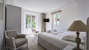Una camera d'albergo con un letto, una sedia, una scrivania, una lampada e due finestre.