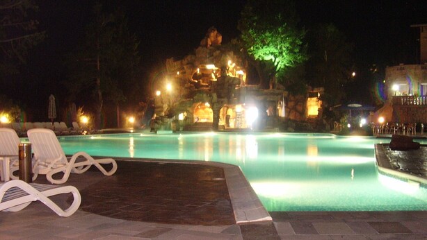 A nighttime pool area with lounge chairs and a stone-tiled deck. - Spacious, Well-Equipped Villa With Stunning Views & Multiple Leisure Opportuni (Batak)