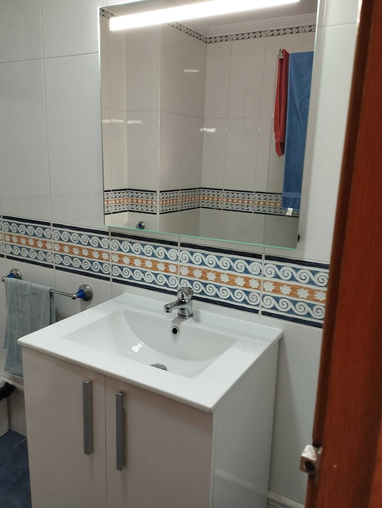 A bathroom with a white sink, a mirror above it, and decorative tiles on the walls.