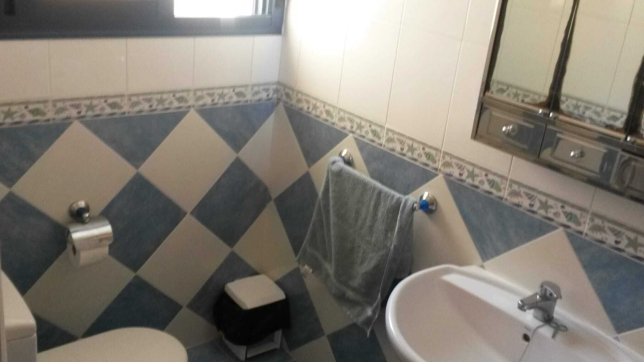 Un baño con piso a cuadros, un lavamanos, un inodoro y un espejo.