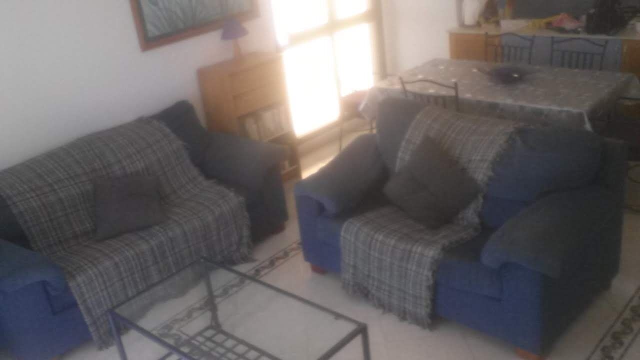 Una sala de estar con dos sofás, una mesa de centro y una mesa de comedor.