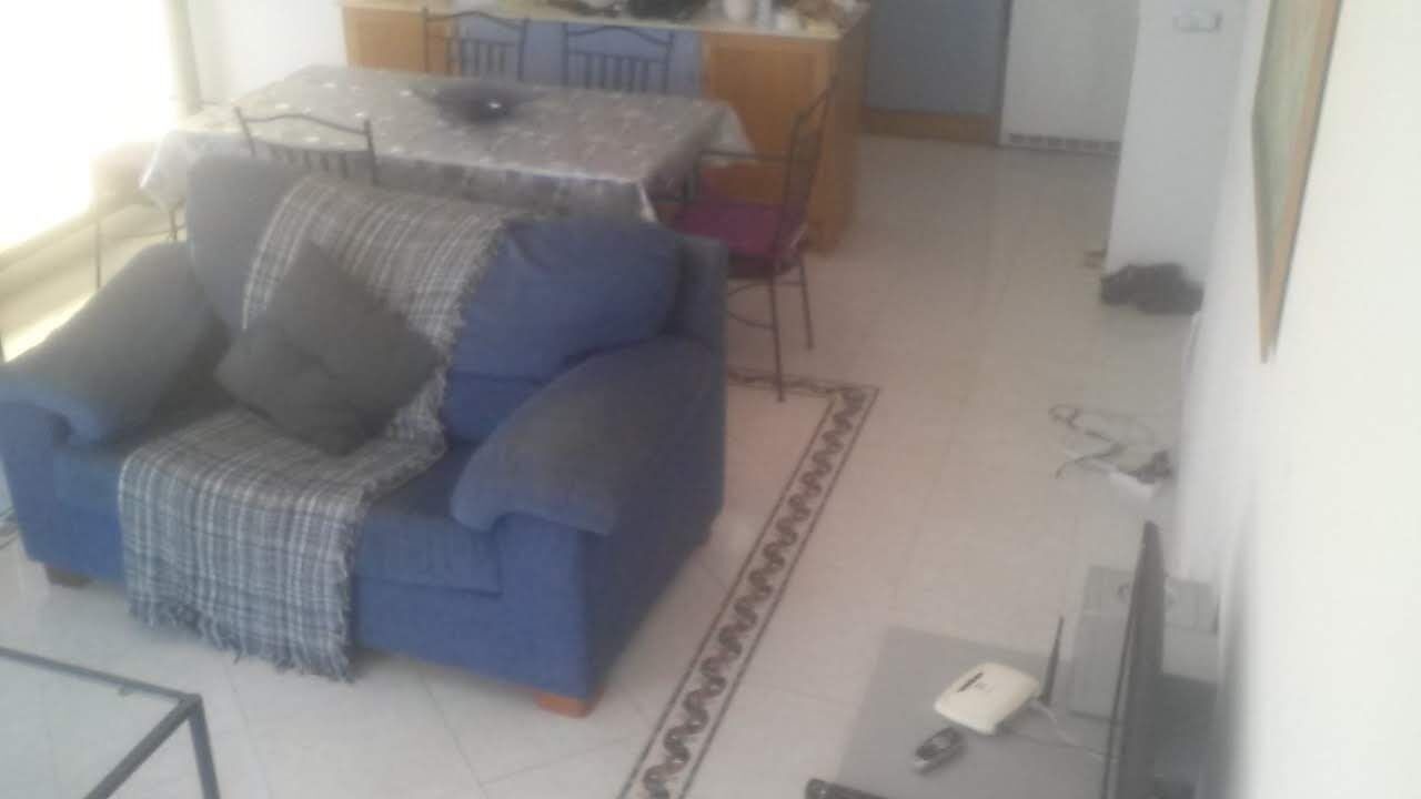 Een woonkamer met een blauwe bank, een eettafel en een televisie.