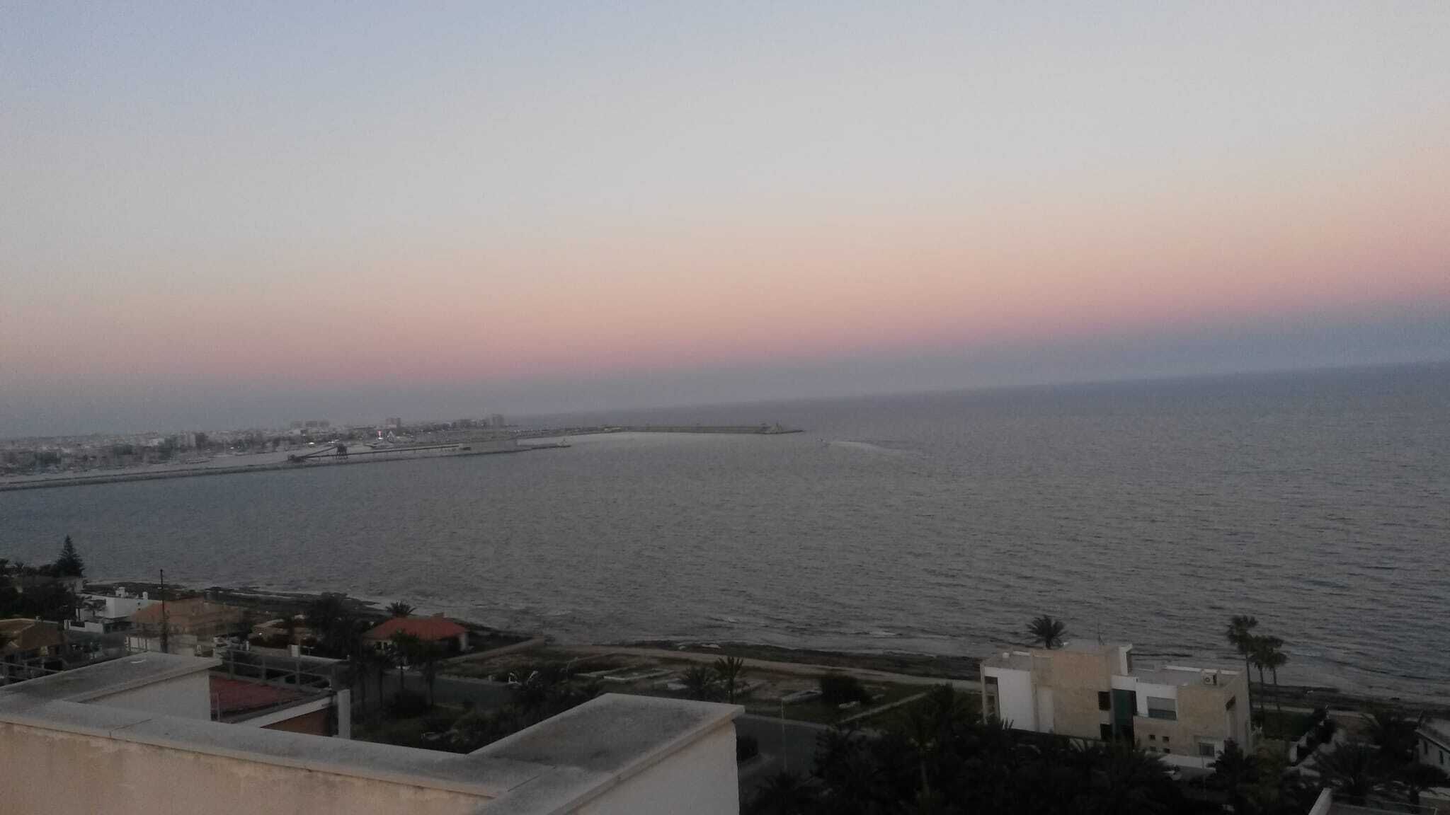 A coastal cityscape with a view of the sea and a distant shoreline.