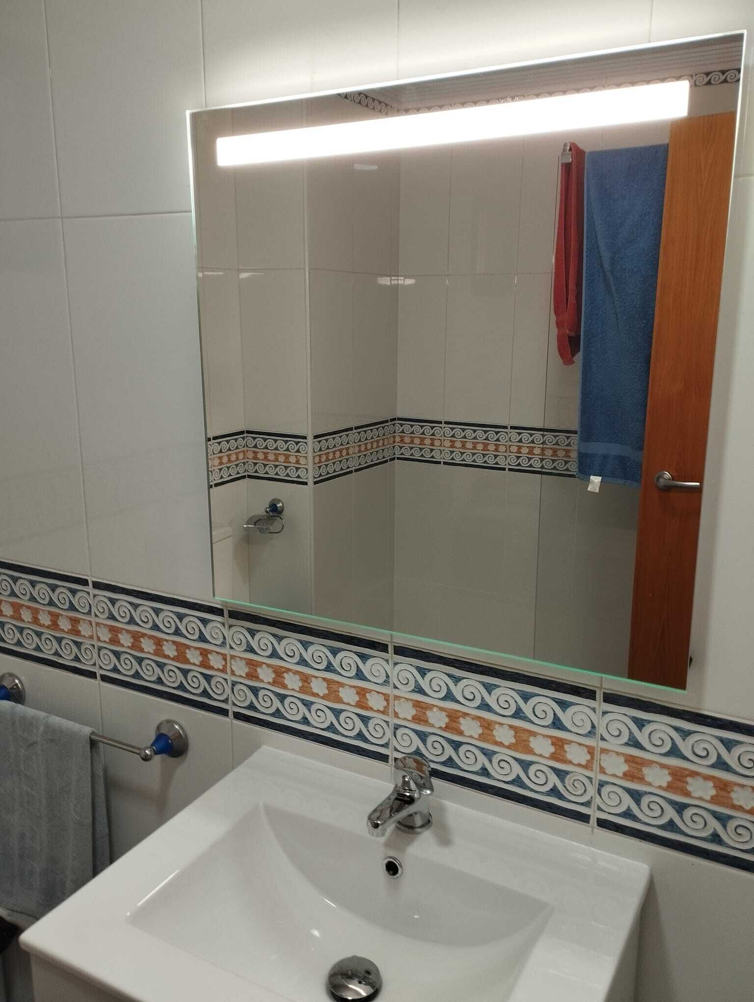 A bathroom with a white sink, a mirror, and tiled walls.