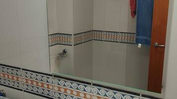 A bathroom with a white sink, a mirror, and tiled walls.