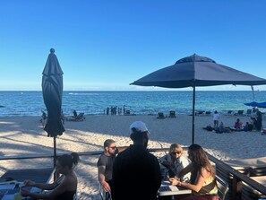 A beachside café with outdoor seating, umbrellas, and a view of the ocean.