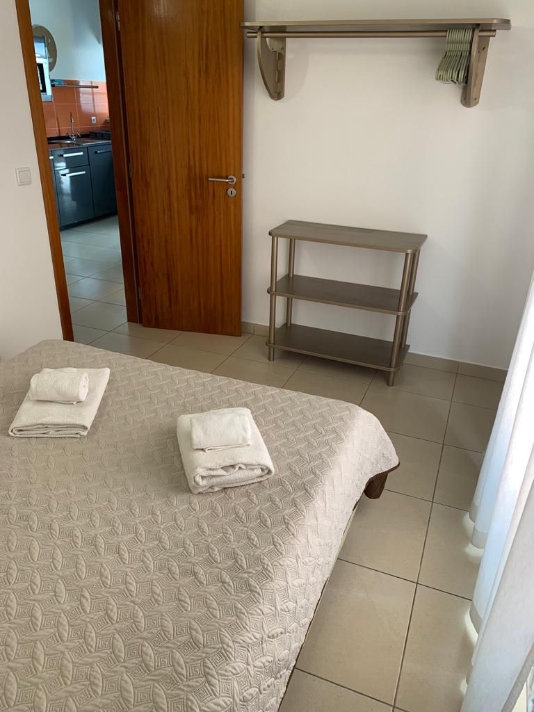 Ein Hotelzimmer mit einem Bett, einer Holztür, einem kleinen Tisch und einem Regal.