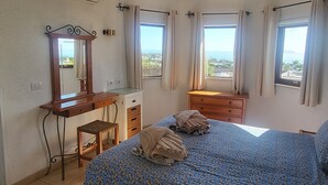 A bedroom with a bed, a dresser, a desk, and a window with curtains. - Amazing panoramic sea views!!! (Playa Blanca)