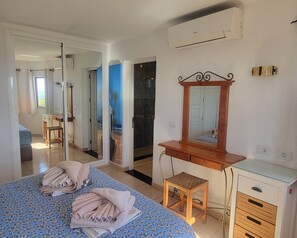 A bedroom with a bed, a dresser, a mirror, and a shower area. - Amazing panoramic sea views!!! (Playa Blanca)