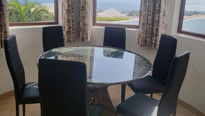 A round glass table with six black chairs in a room with large windows and curtains. - Amazing panoramic sea views!!! (Playa Blanca)